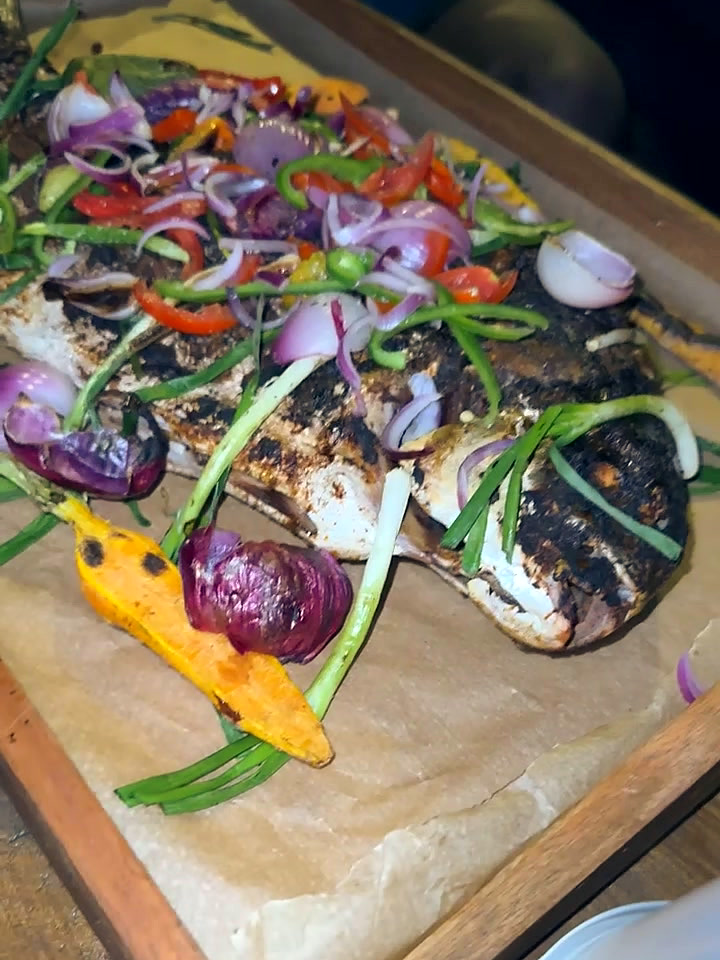 The grilled Pompano on its wooden serving board, whole, dressed and brought to the table