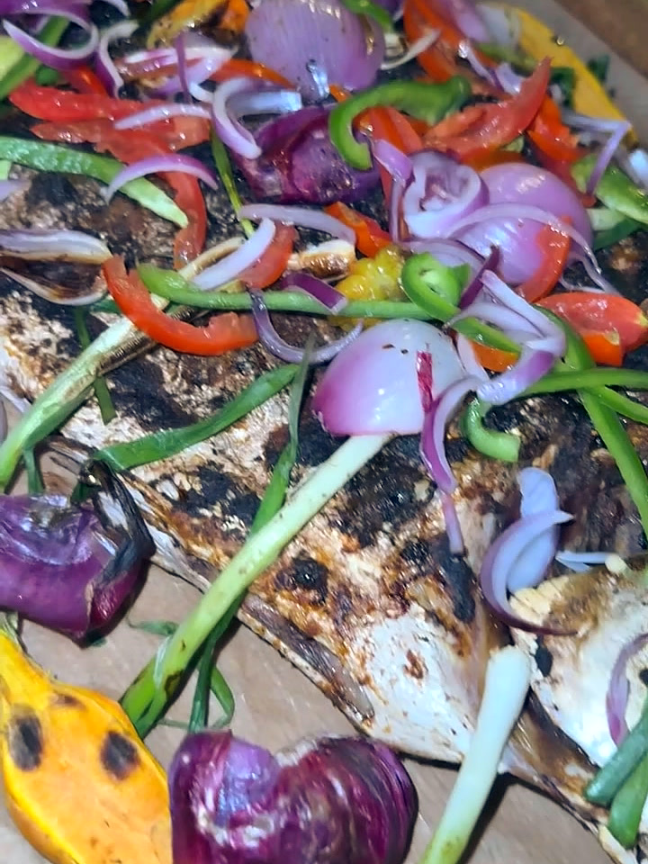 A whole Pompano grilled over fire at Marsaiah, dressed with sweet peppers, red onion, spring onion and plantain